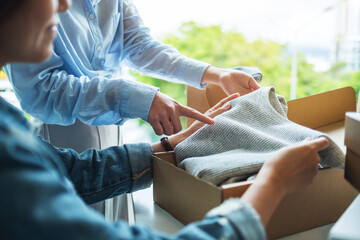 Two young women receiving and opening a postal parcel box of clothing at home for delivery and online shopping concept