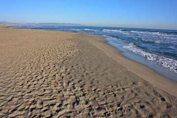 Fototapeta na wymiar relaxing walks on the sandy beach of Versilia on a sunny day in Italian winter