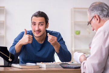 Young man visiting old male jeweler