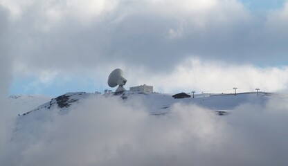 Satellite dish located on top of a snowy mountain.