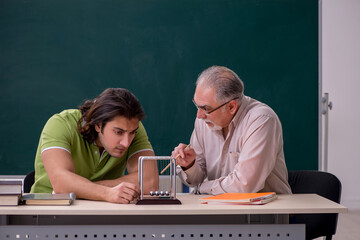Old professor physicist and young student in the classroom