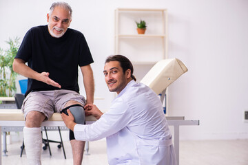Obraz premium Old injured man visiting young male doctor traumatologist