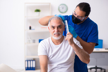 Old man visiting young male doctor in hair transplantation conce