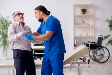 Fototapeta premium Old patient visiting young male doctor