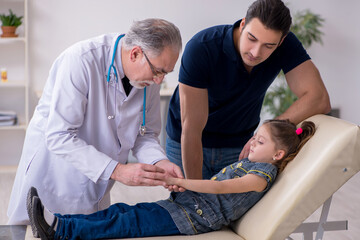 Young father and his daughter visiting old male doctor