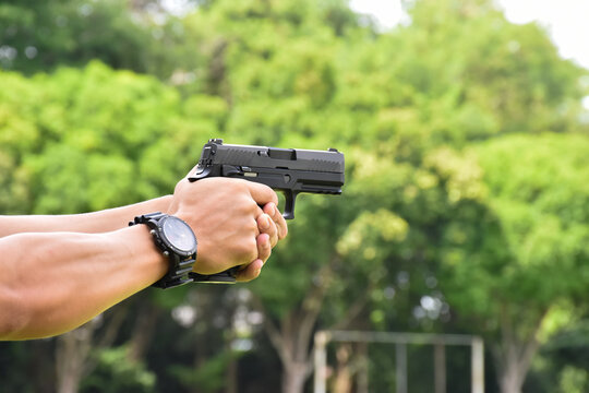 Black short shooting gun in hand ready to shoot and after shooting.