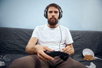 Man sitting on sofa wearing headphones with gamepad playing food leisure technology lifestyle © SHOTPRIME STUDIO