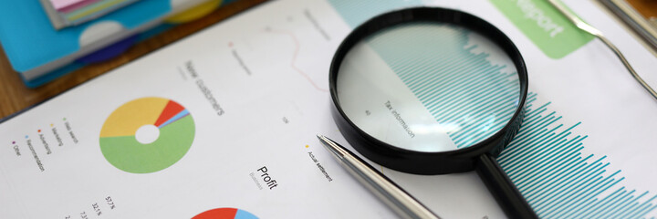 Business chart with silver pen on wooden table closeup background.