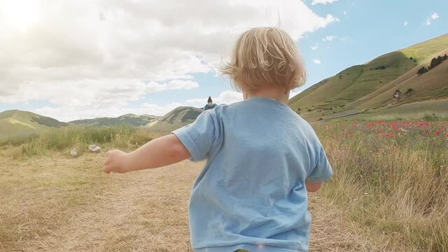 Toddler running to his mom in a green meadow. Slow-motion