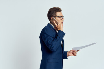 Business man in a suit talking on the phone with glasses with documents technology official