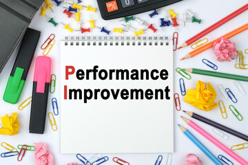 On the table is a calculator, diary, markers, pencils and a notebook with the inscription - Performance Improvement