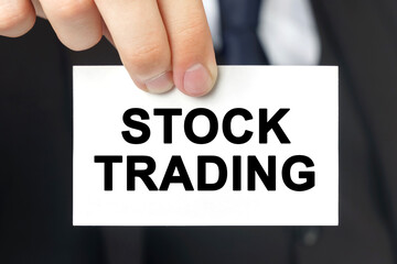 Businessman shows a card with the text - STOCK TRADING