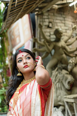 Portrait of stunning Indian woman draped in traditional saree adorned with gold jewellery, posing...