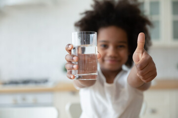 Focus on happy small african american girls hands holding glass with fresh pure water and showing...