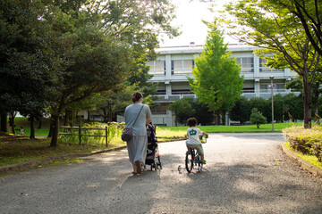公園を自転車とベビーカーで散歩する日本人の親子