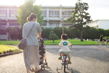 公園を自転車とベビーカーで散歩する日本人の親子