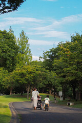 公園を自転車とベビーカーで散歩する日本人の親子