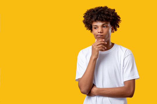 Pensive black teenager. Difficult decision. Confused african student with hand on chin isolated on orange copy space. Disapproving emotion. Think idea. Advertising background