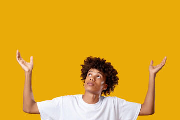 Thanks god. Find inspiration. African teenager boy holding hands up isolated on orange copy space....