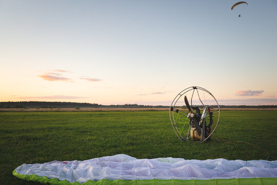 Individual parajet backpack with a no-spin engine and spread wing on the takeoff field. Wing flight preparation. Extreme sports. Paragliding and small aircraft.