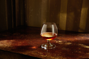 view of glass of  cognac on brown color wooden table surface