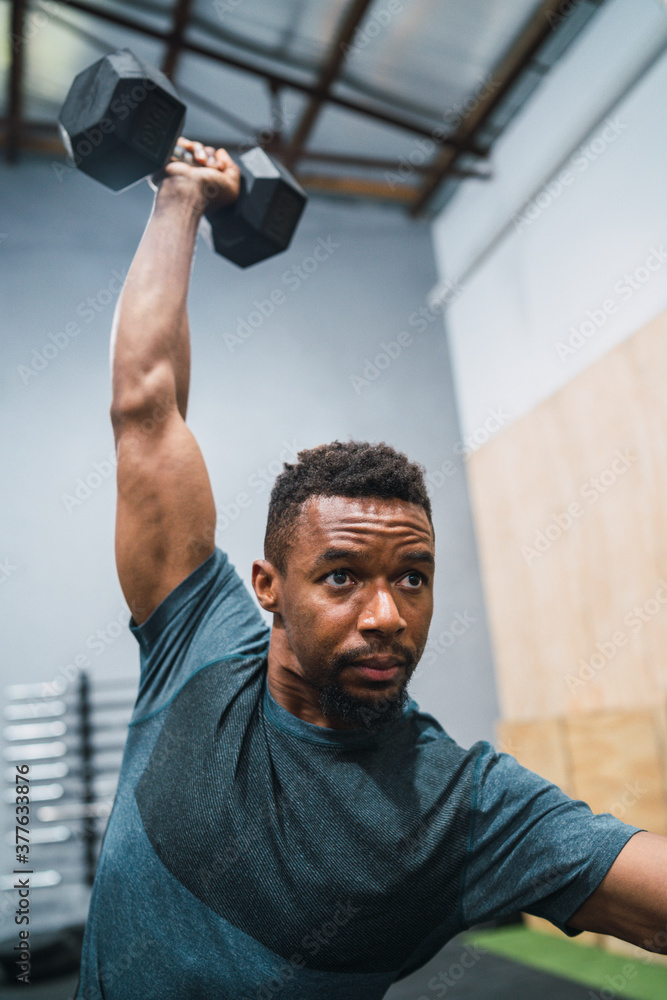 Wall mural Crossfit athlete doing exercise with dumbbell.