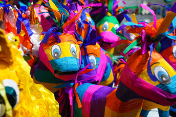 A market display of brightly coloured piñatas, decorated containers filled with sweets and toys, which are traditionally used or celebration in Mexico.