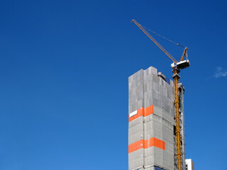 grey canvas sheet covered building structure for safety with tower crane working on rooftop with clear sky copy space