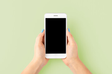 Overhead shot of woman’s hand with blue nails using mobile phone with empty screen