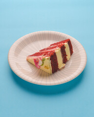 A slice of red velvet cake with white frosting and a little rose flower on top. Traditional red velvet cake recipe.