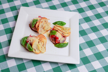 Traditional Italian appetizer Bruschetta with roasted tomatoes, mozzarella cheese, strawberry, garlic and herbs.