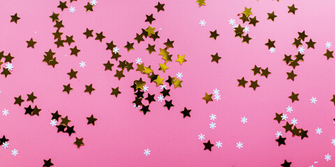 Stars and snowflakes on a pink background, from above