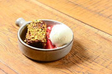 Brownie dessert with ice cream and fresh organic strawberry. Served in a traditional bowl. Georgian cuisine concept.