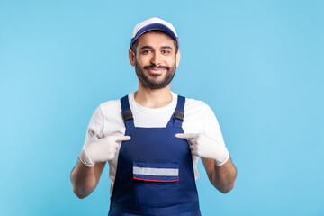 This is me! Happy satisfied handyman in overalls and hygiene gloves pointing himself, proud of...