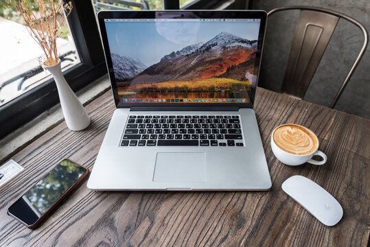 SONGKHLA, THAILAND - July 7, 2018: Apple Macbook pro computer with Magic mouse, iPhone X and latte art coffee on wooden table, created by Apple Inc.