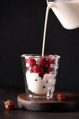 ripe raspberries with cold milk in a glass