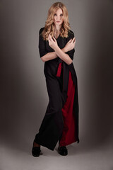 Fototapeta premium A slender girl in black and red clothes on a gray background.