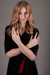 A slender girl in black and red clothes on a gray background.