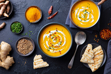 Pumpkin soup with spices in black bowl. Comfort detox food. Dark background. Top view.