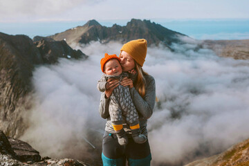 Mother kissing infant baby family hiking in mountains active vacations travel outdoor woman with...