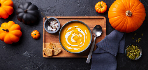 Pumpkin, butternut squash cream soup in black bowl. Hallowen, Thanksgiving day decoration. Top view.