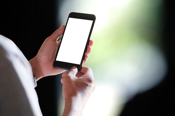 Close up of man holding smart phone with blank screen and blurred background.