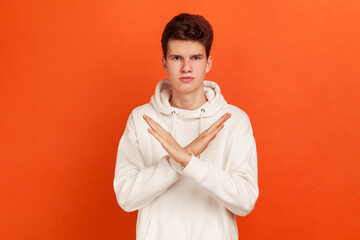 There is no way! Serious concentrated young man in stylish hoodie showing no gesture crossing arms,...