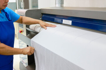 A laundry staff is ironing a bedsheet with Industrial ironing machine. Shot taken in the factory