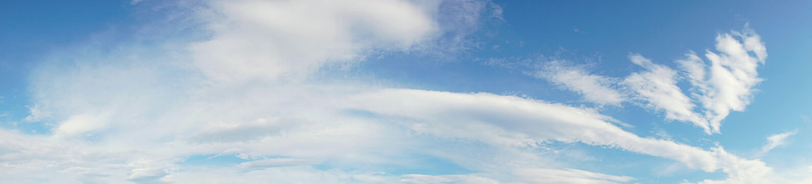 Panoramic of a long white cloud over a large blue sky