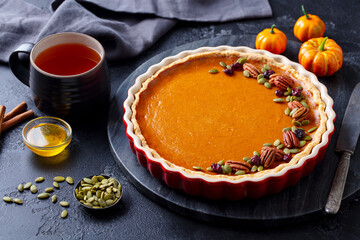Pumpkin pie on marble board with cup of tea. Grey background. Close up.