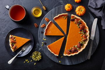 Pumpkin pie on marble board with cup of tea. Grey background. Top view.