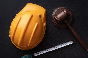 Wooden judge gavel, yellow building helmet and tape. Labor-related legal concept. Top view