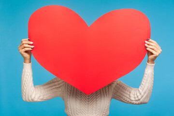 Woman in white knitted sweater hiding behind red paper heart, charity, help and support, healthcare...