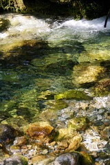 Kleiner Gebirgsbach mit kristallklarem Wasser und nasse Steine